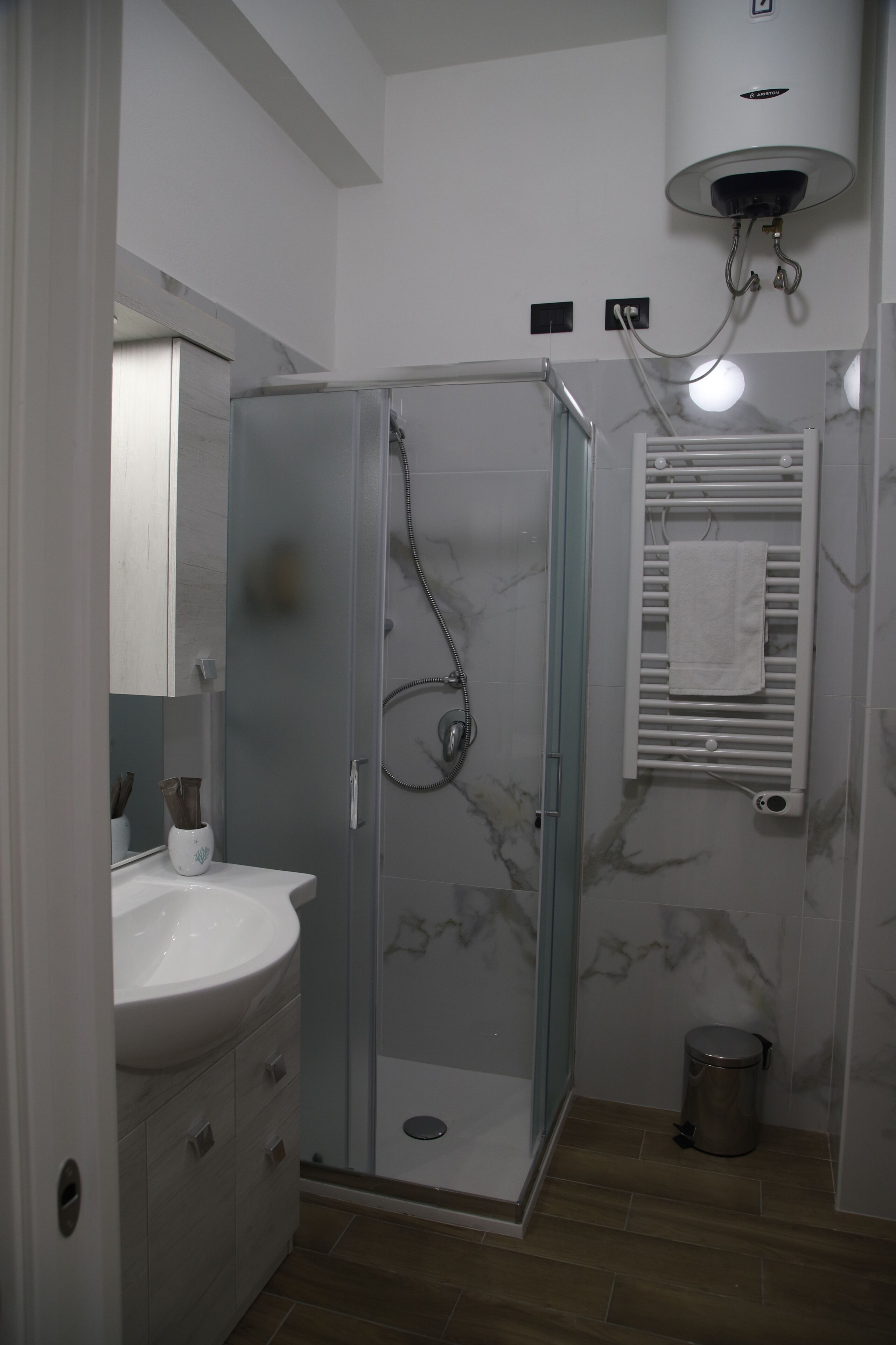 A bathroom with a glass-enclosed shower, a white sink, and a towel rack.