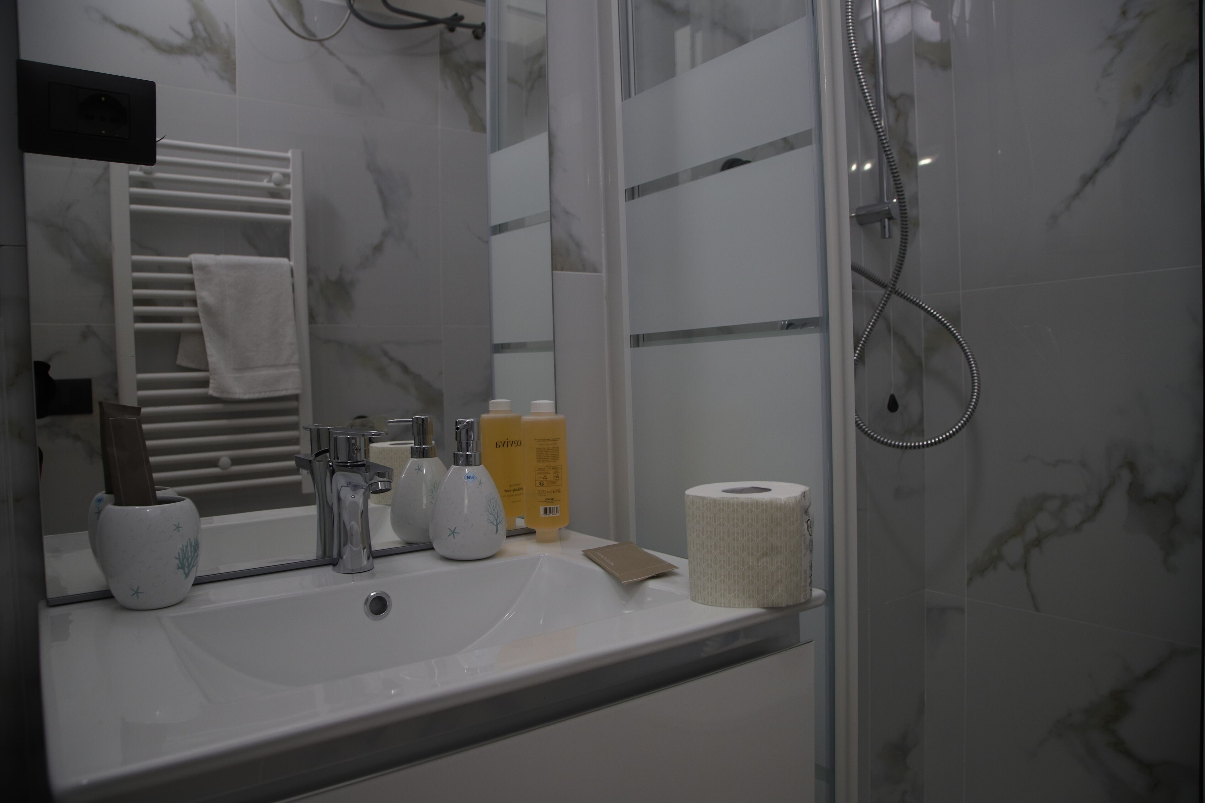 A bathroom with a white sink, mirror, towel rack, and shower.