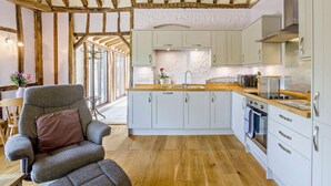 A modern kitchen with white cabinets, a wooden ceiling, and a central island. - 1 Bed in Dunmow (oc-51222) (Thaxted)