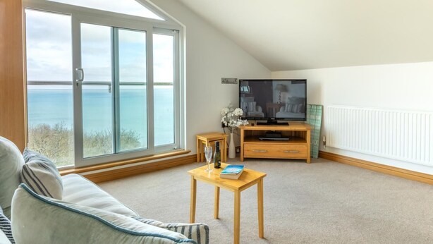 A living room with a large window, a flat-screen TV, a wooden coffee table, and a sofa. - 2 Bed in Torquay (oc-51143) (Torquay)