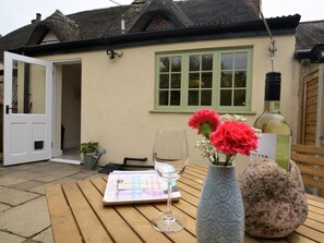 A table with a book, a wine glass, and a vase with flowers. - 1 Bed in Sherborne (oc-51018) (Thornford)