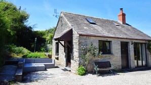 A stone building with a sloped roof, a chimney, and a bench outside. - 3 Bed in Padstow (oc-51214) (Padstow)