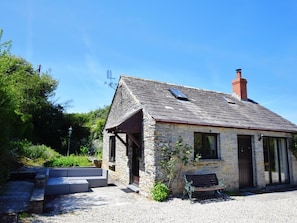 A stone building with a sloped roof, a chimney, and a bench outside. - 3 Bed in Padstow (oc-51214) (Padstow)