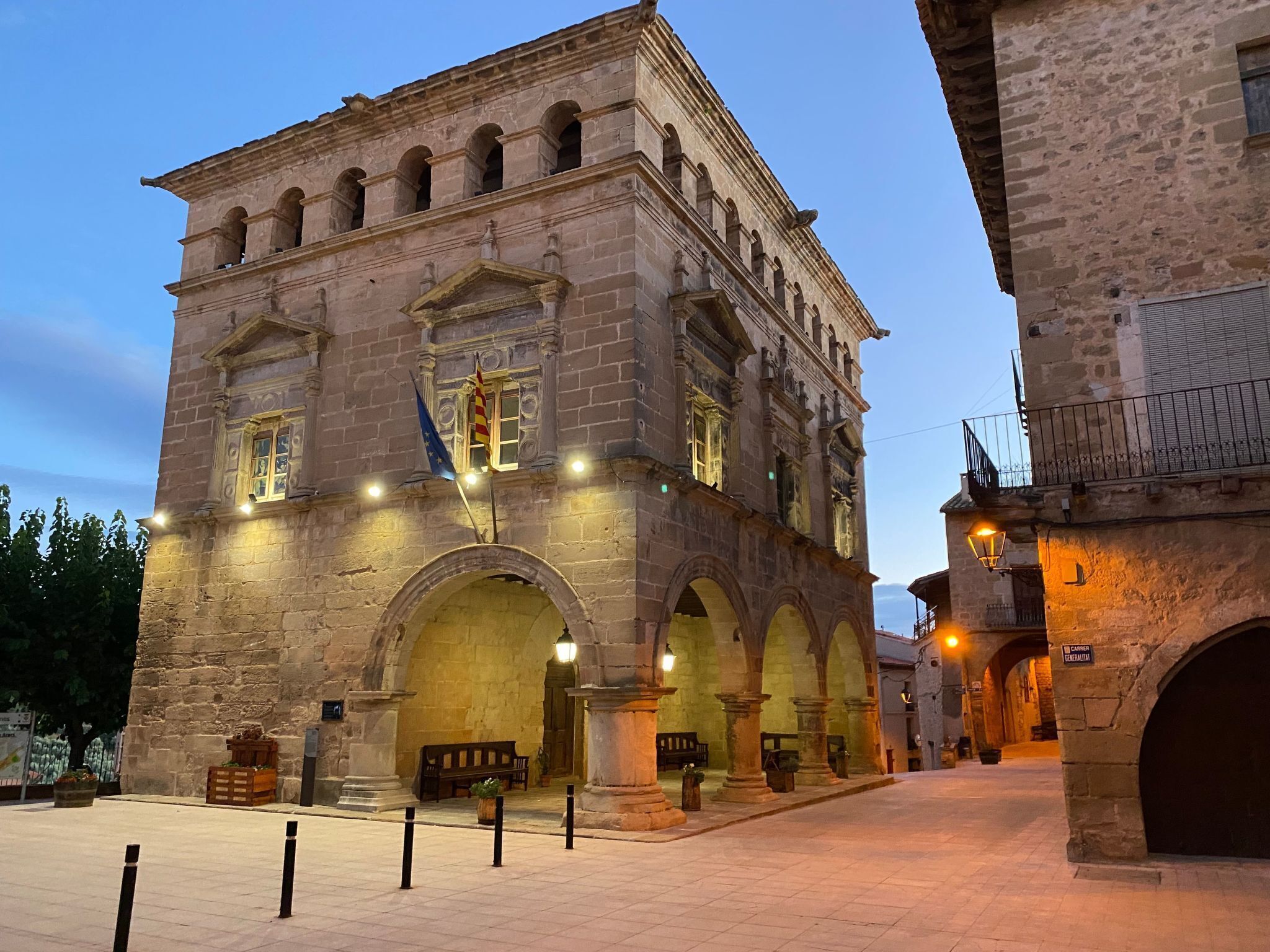 Un edificio histórico de piedra con varios arcos y una bandera.