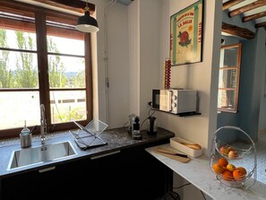 A kitchen with a window, a sink, a toaster, and a fruit basket.