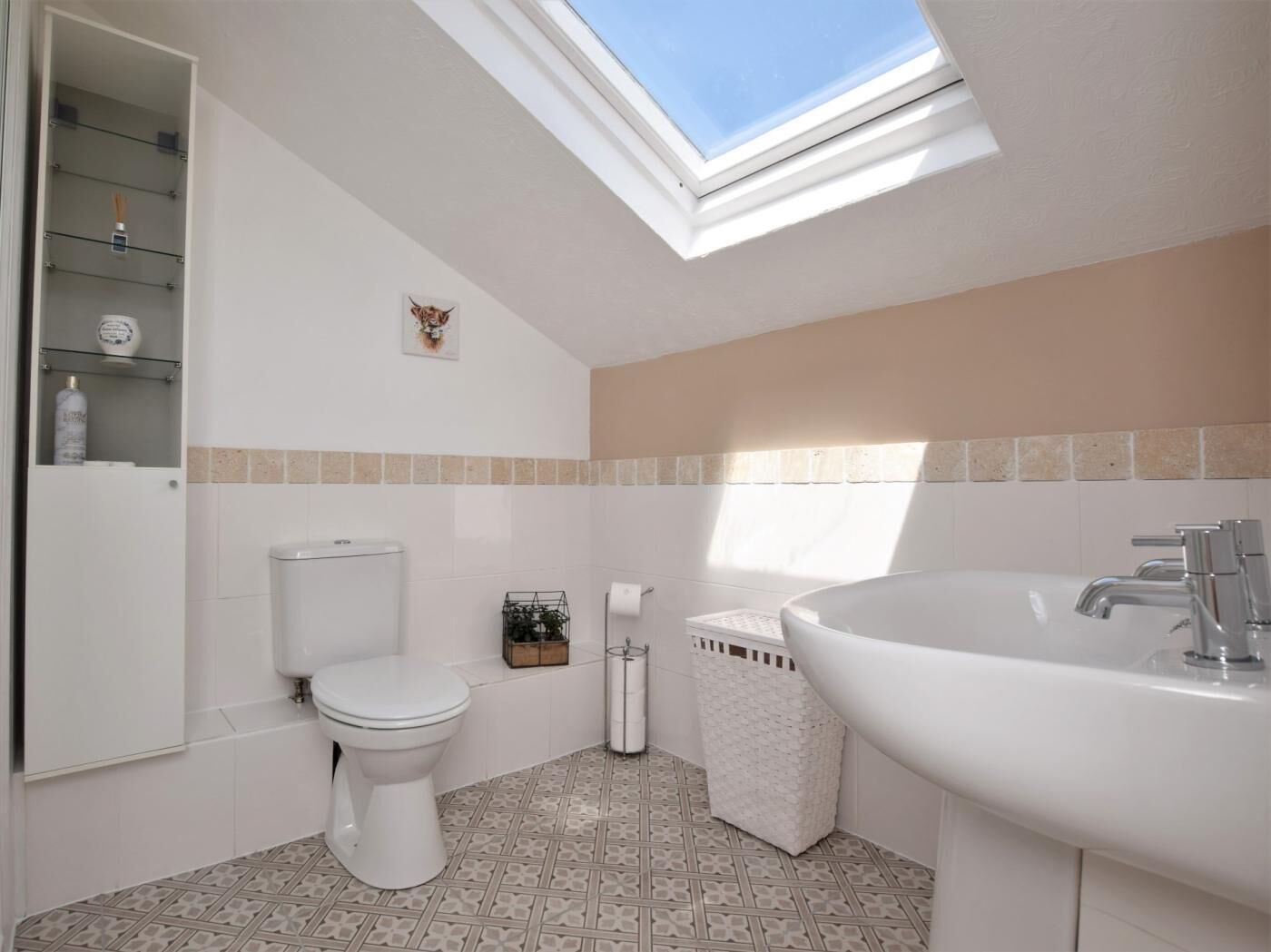 Une salle de bain dotée d’une lucarne, de toilettes, d’un lavabo et d’un espace douche.