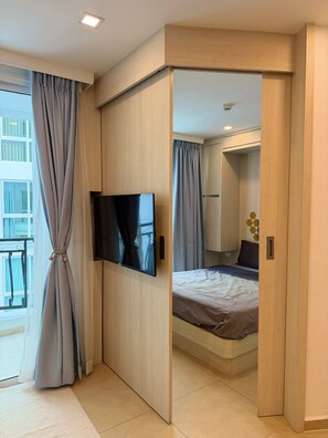 A modern bedroom with a TV, a bed, and a wardrobe. - Enjoy your vacations at lovely condo with pool view condo. (Pattaya City)