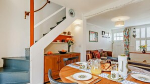 A dining area with a wooden table set for four, a staircase, and a kitchen area with a shelf. - 2 Bed in York (oc-51740) (York)