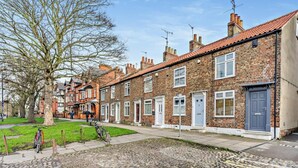 A row of terraced houses with brick facades, a cobblestone street, and a tree-lined sidewalk. - 2 Bed in York (oc-51740) (York)
