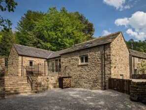 A stone building with a small porch and a gravel driveway. - 2 Bed in Bakewell (oc-skn18) (Baslow)