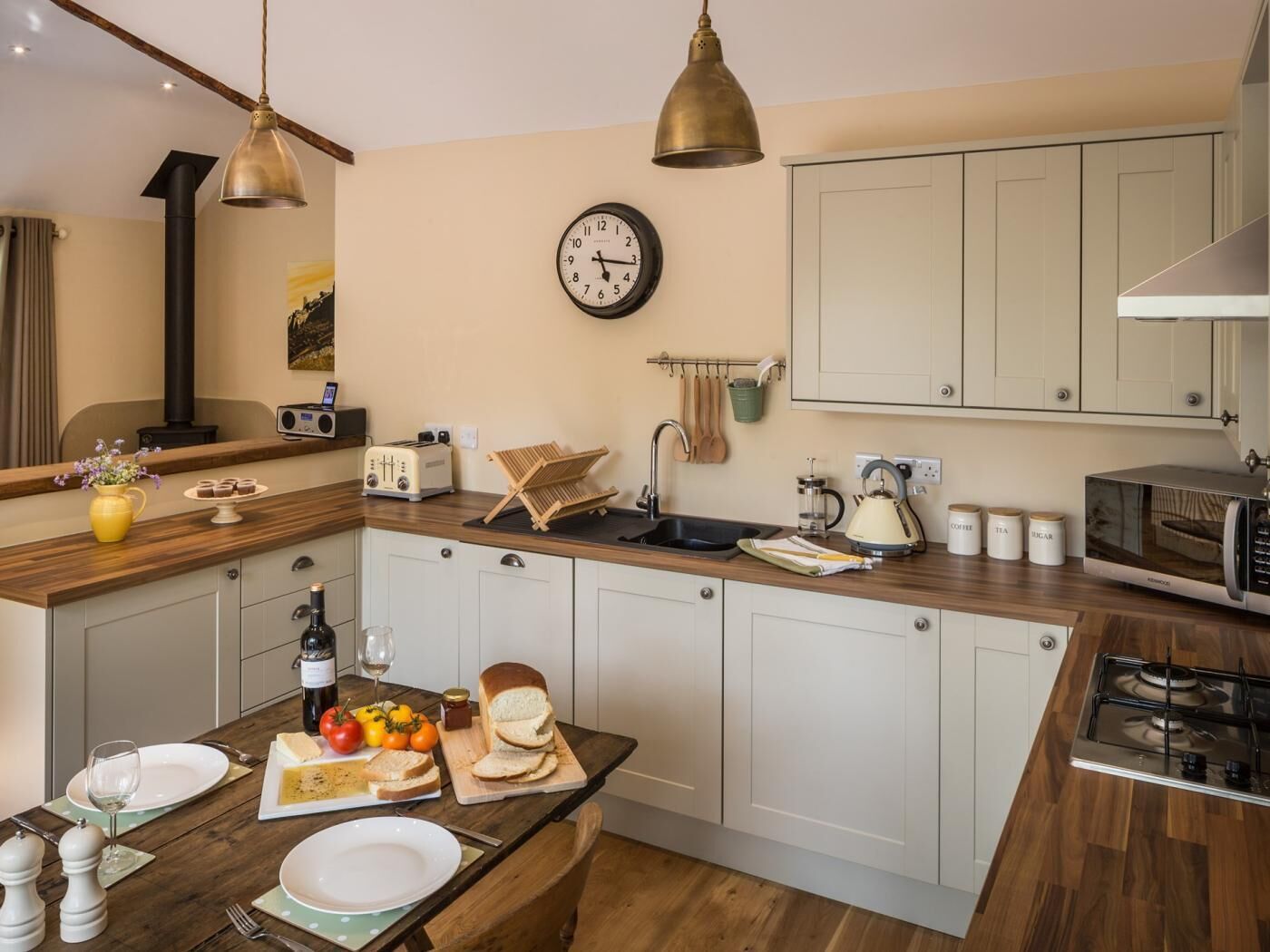A modern kitchen with a wooden countertop, a built-in stove, and a clock on the wall.
