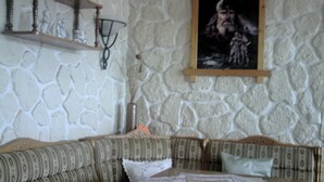 Een kamer met een stenen muur, een houten plank met decoratieve spullen, een lijst met foto en een gestreept sofa.