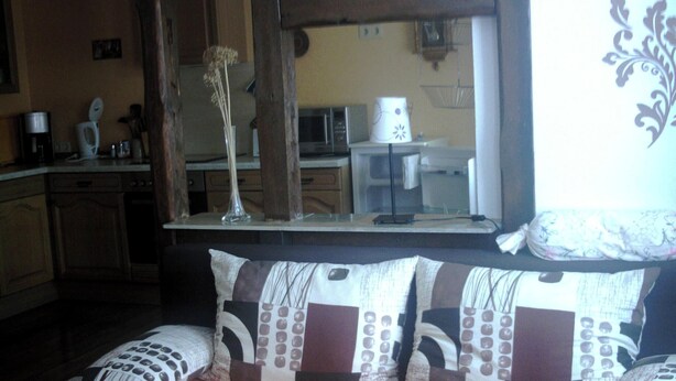 Een kamer met een bank, een koffiezetapparaat en een magnetron, zichtbaar door een raam.