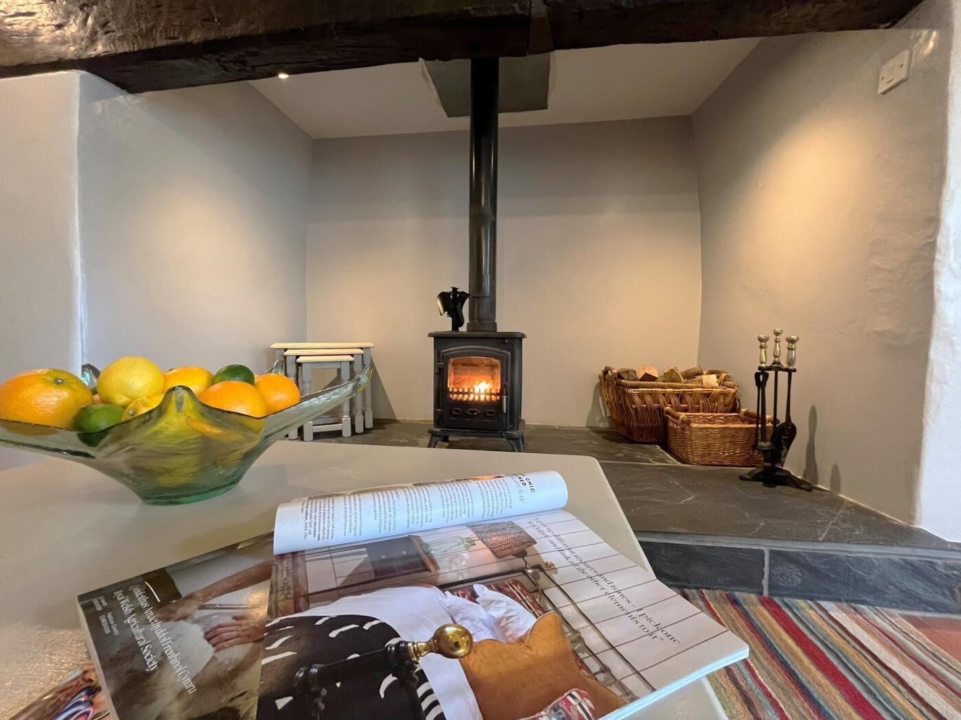 A cozy room with a fireplace, a bowl of fruit, and a magazine on a table.