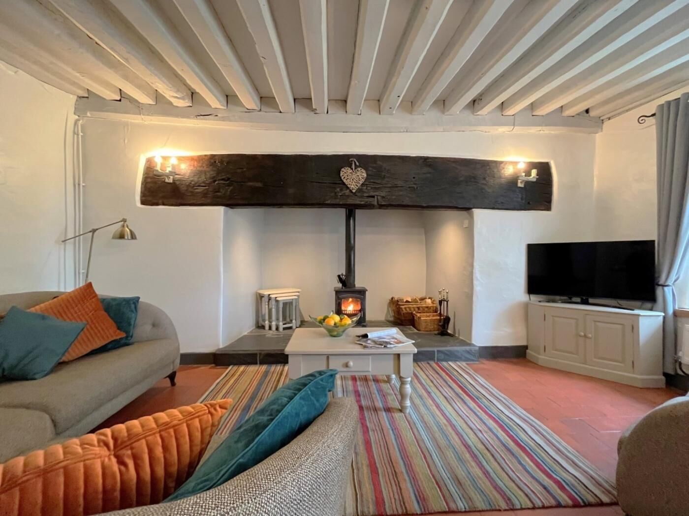 A living room with a sofa, a coffee table, a television, a fireplace, and a striped rug.