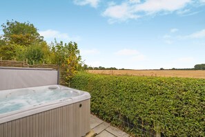 A hot tub in a garden with a hedge and a field in the background. - 2 Bed in Diss (oc-51468) (Burgate Little Green)