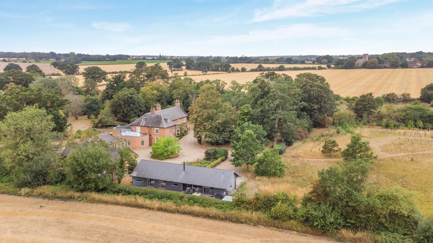 A rural property with a large house surrounded by fields and trees.