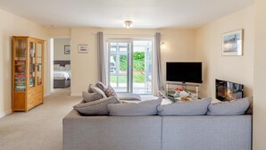 A living room with a grey sofa, a television, and a fireplace. - 3 Bed in Bideford (oc-51790) (Hartland)