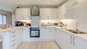 A modern kitchen with white cabinets, a built-in oven, a microwave, and a sink. - 2 Bed in Beaworthy (oc-52087) (Virginstowe)