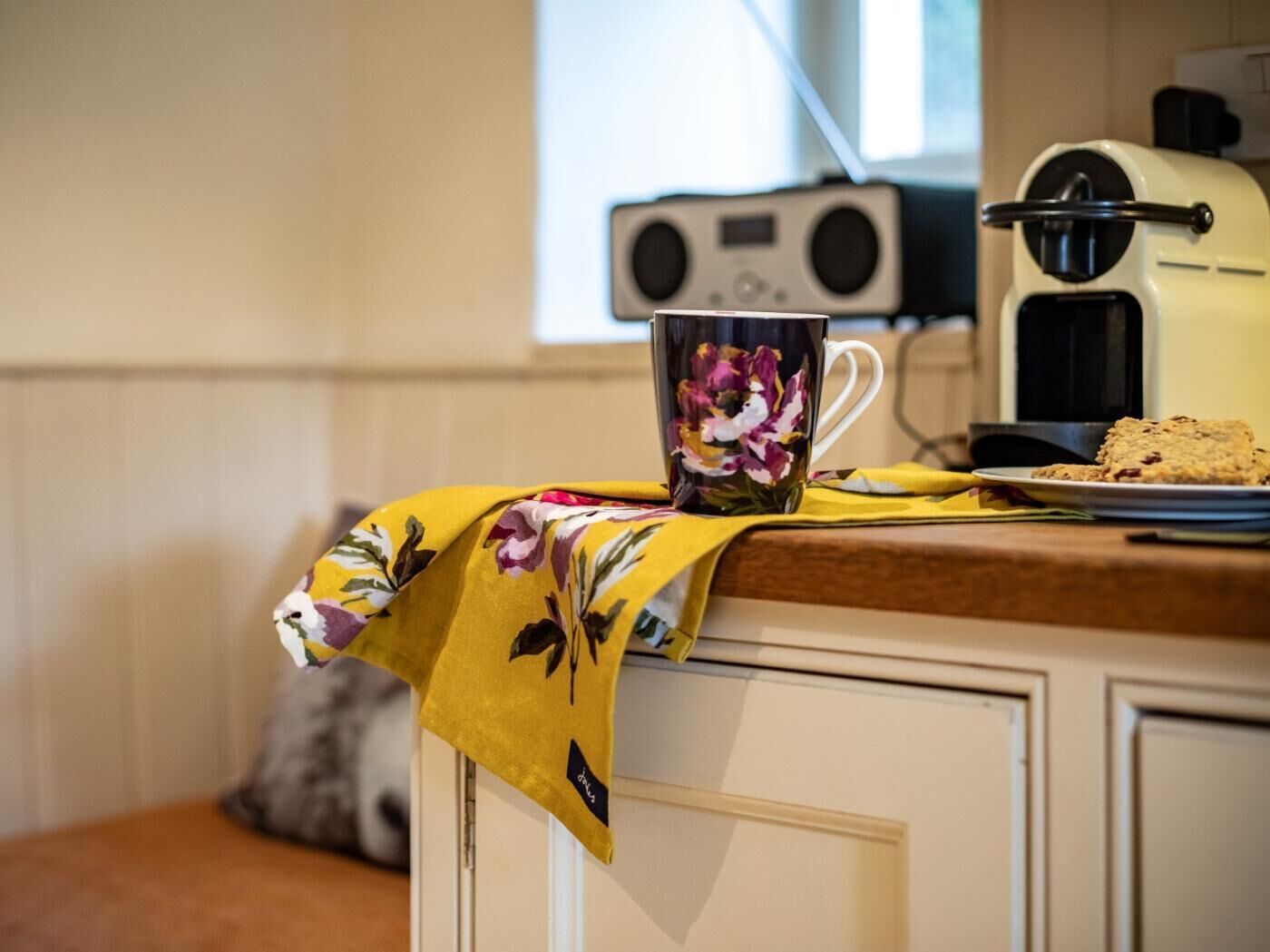 Une cuisine équipée d’une machine à café, d’une tasse et d’une assiette remplie de biscuits.