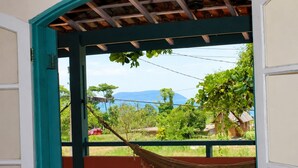 A room with a hammock, a view of greenery and mountains, and a wooden ceiling. - Family home in Lagoinha: sea view, barbecue and 24-hour security. (Ubatuba)