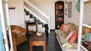 A living room with a sofa, a wicker chair, a wooden coffee table, a staircase, and a bookshelf. - Family home in Lagoinha: sea view, barbecue and 24-hour security. (Ubatuba)