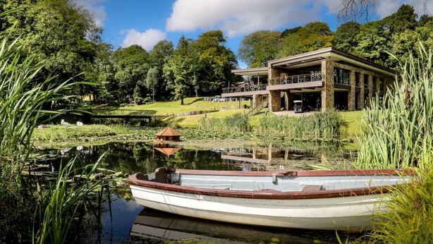 A lakeside building with a dock, surrounded by lush greenery and trees. - 3 Bed in Wylam (oc-51738) (Wylam)