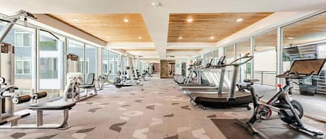 A gym with cardio machines, weight equipment, and a patterned carpet.