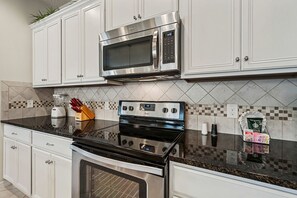 A kitchen with white cabinets, a stainless steel microwave, a black stove, and a tiled backsplash. - Sleeps 10*Private Pool*Clubhouse Amenities (Kissimmee)