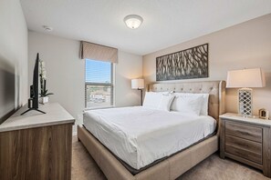 A bedroom with a bed, bedside tables, a TV, and a window with blinds. - Sleeps 10*Private Pool*Clubhouse Amenities (Kissimmee)