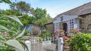A stone building with a white door, surrounded by a gravel path and a white fence. - 1 Bed in Bude (oc-51546) (Gooseham)