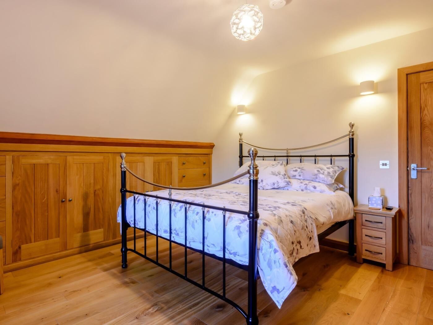 Une chambre à coucher avec une armoire en bois, un cadre de lit en métal, une table de chevet et une porte.