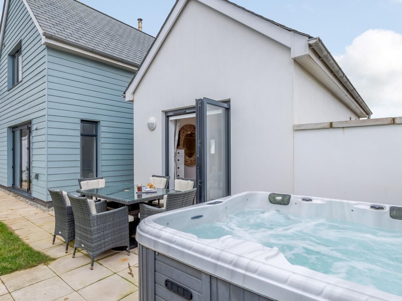 Ein Whirlpool in einem Garten mit einem Patio-Tisch und Stühlen.