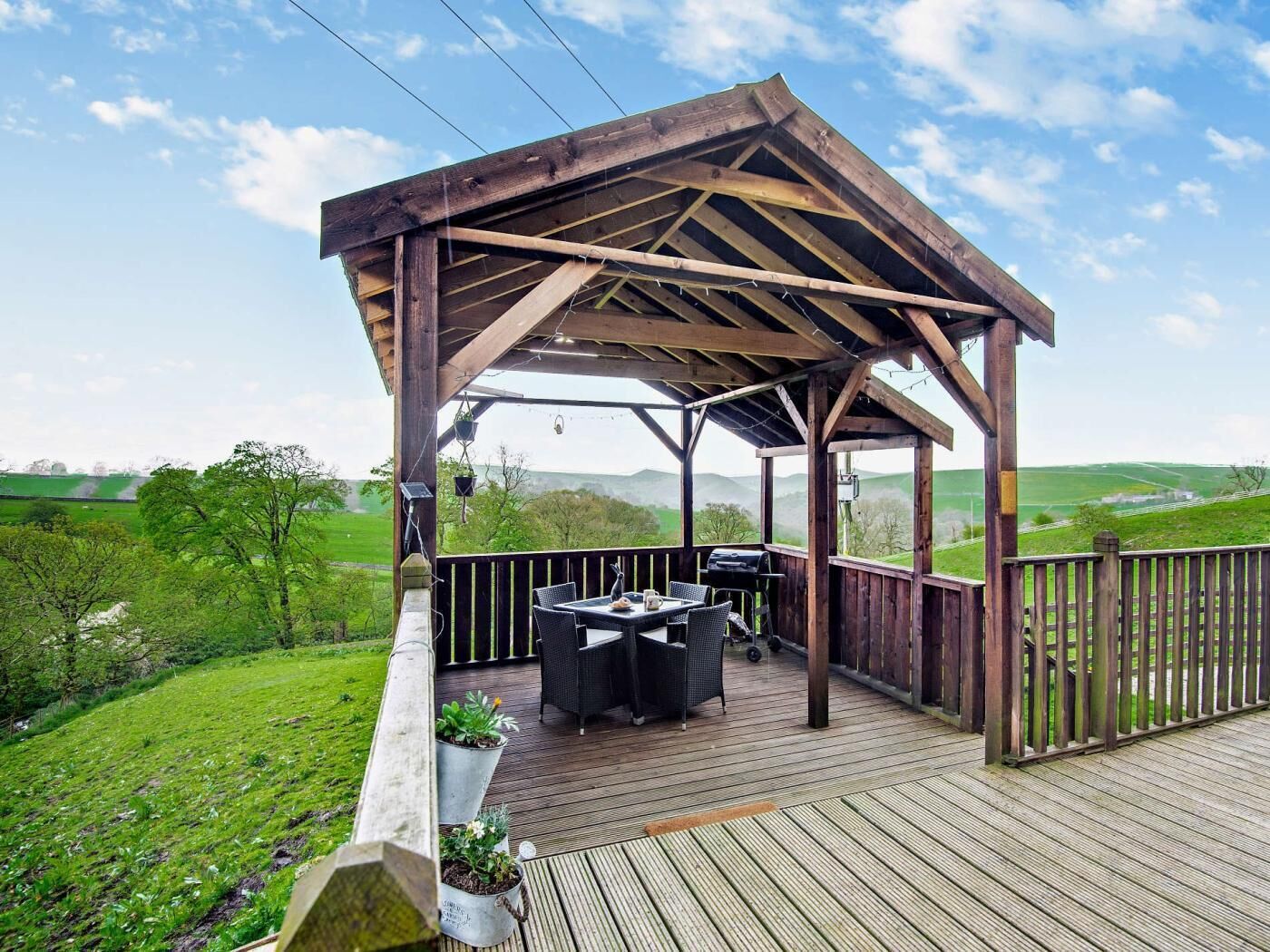 A wooden deck with a pergola, outdoor furniture, and a grill.