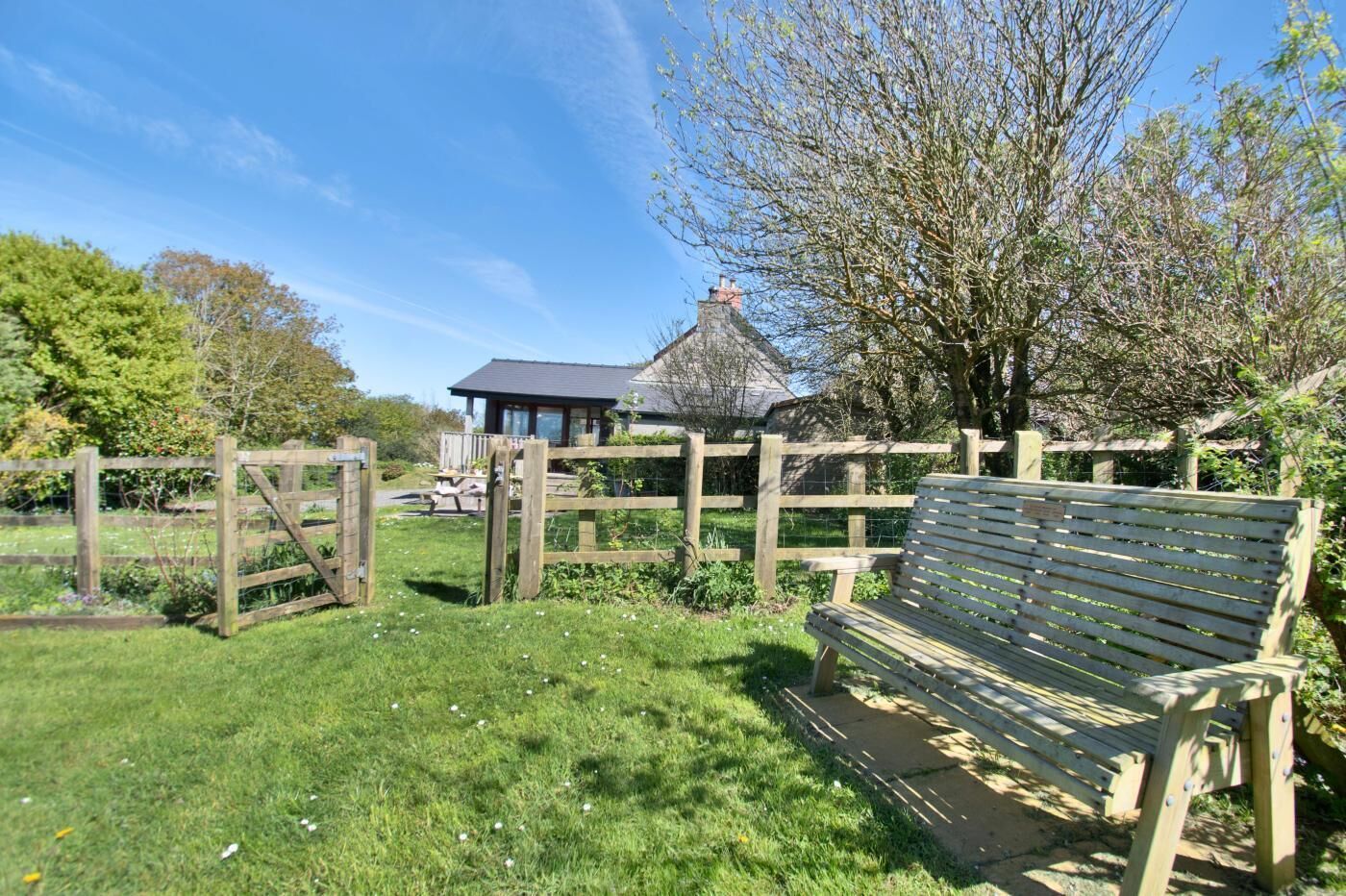 A wooden bench in a grassy area with a rustic building in the background.