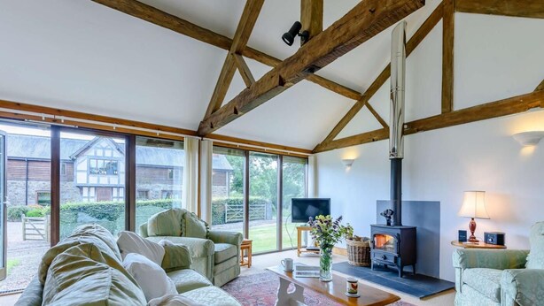A spacious living room with a large sofa, a television, a fireplace, and a view of the outside. - 2 Bed in Presteigne (oc-chl34) (Kinnerton)