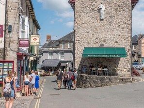 Ein Steinhaus mit einer grünen Markise, einem Schild für ‚Shepherds Ice Cream Parlour & Coffee Bar‘ und einem McCarneys Schild.