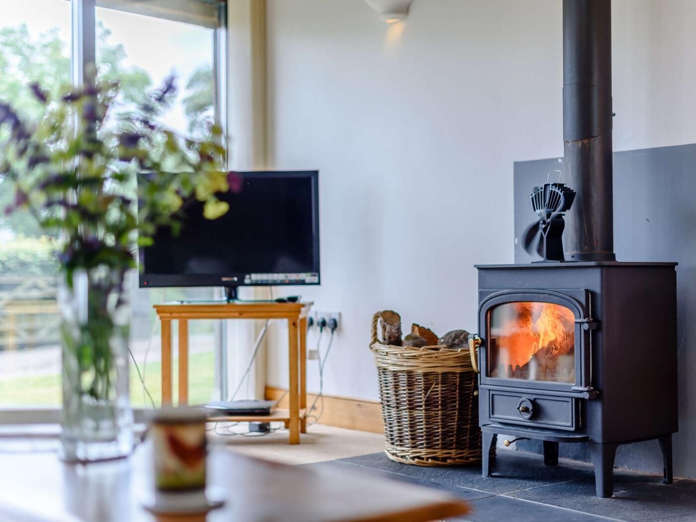 A modern living room with a television, a fireplace, and a wicker basket.