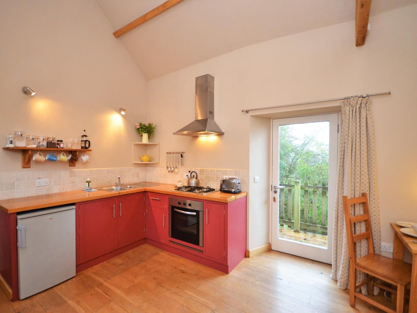 A compact kitchen with a built-in oven, a small refrigerator, and a gas stove.