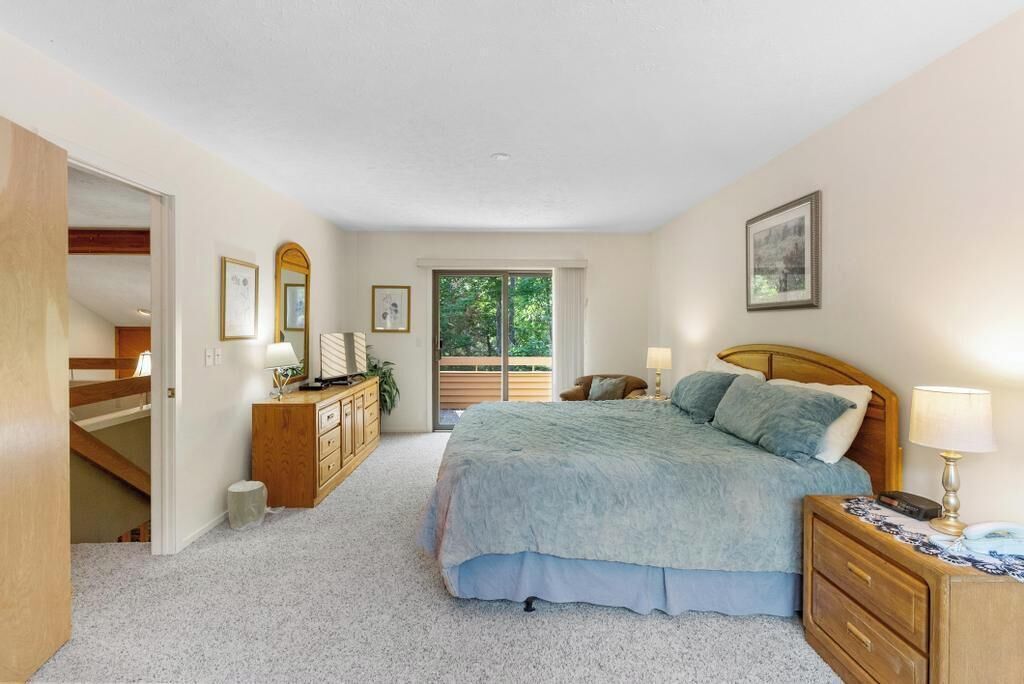 Een slaapkamer met een bed, nachtkastjes, een dressoir, een raam met uitzicht en een deur naar een andere kamer.