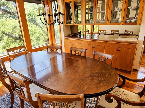 A dining area with a large wooden table, chairs, and a chandelier.
