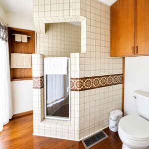A bathroom with a shower, toilet, and a towel rack.