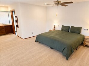 Ein Schlafzimmer mit Bett, Deckenventilator, Nachttisch und Kommode.