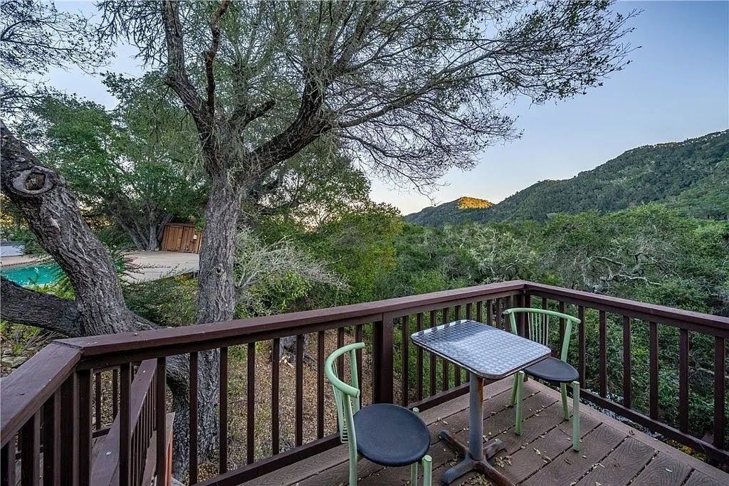 Eine Terrasse mit Tisch und Stühlen mit Blick auf einen Pool und eine gebirgige Landschaft.