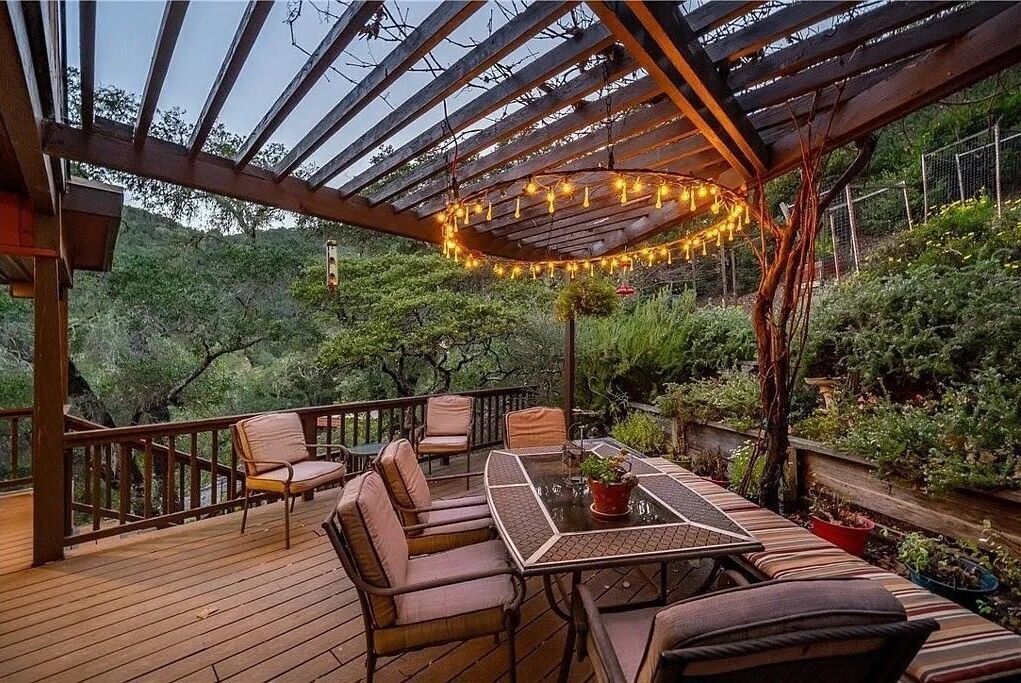Une terrasse extérieure dotée d’une pergola, de sièges et de guirlandes lumineuses.
