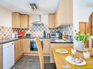 Eine Küche mit Holzausstattung, einer Mikrowelle, einem Toaster und einem Esstisch mit Frühstücksangebot.