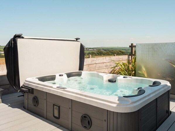 Un bain à remous sur une terrasse extérieure offrant une vue dégagée sur le paysage.