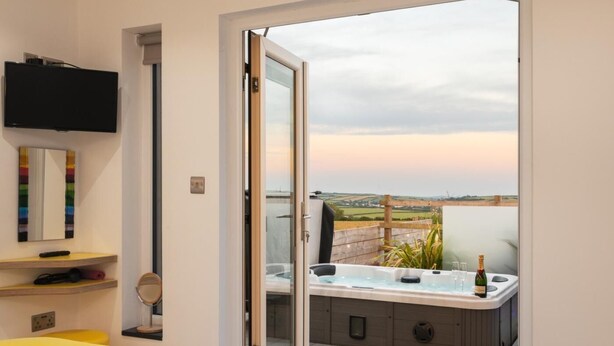 Et soveværelse med seng, fjernsyn, spejl og badeværelse med jacuzzi.