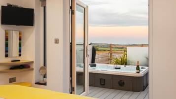 Une chambre à coucher avec un lit, une télévision, un miroir et une salle de bain équipée d’un jacuzzi.