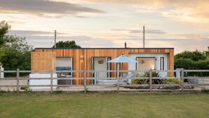 Et moderne hus med træfacade, en lukket have og en klar himmel.